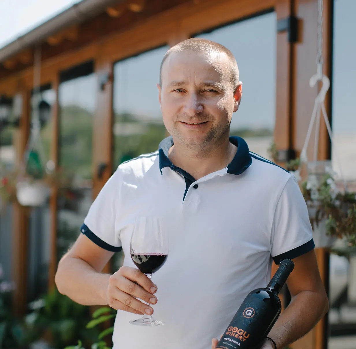 Ilie Gogu cu un pahar de vin roșu pe terasa cramei